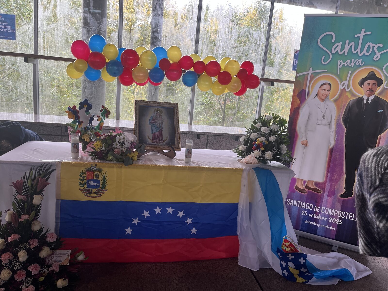 Altar de la Virgen de la Chiquinquirá durante la feria, con flores, bandera venezolana y una pequeña bandera gallega